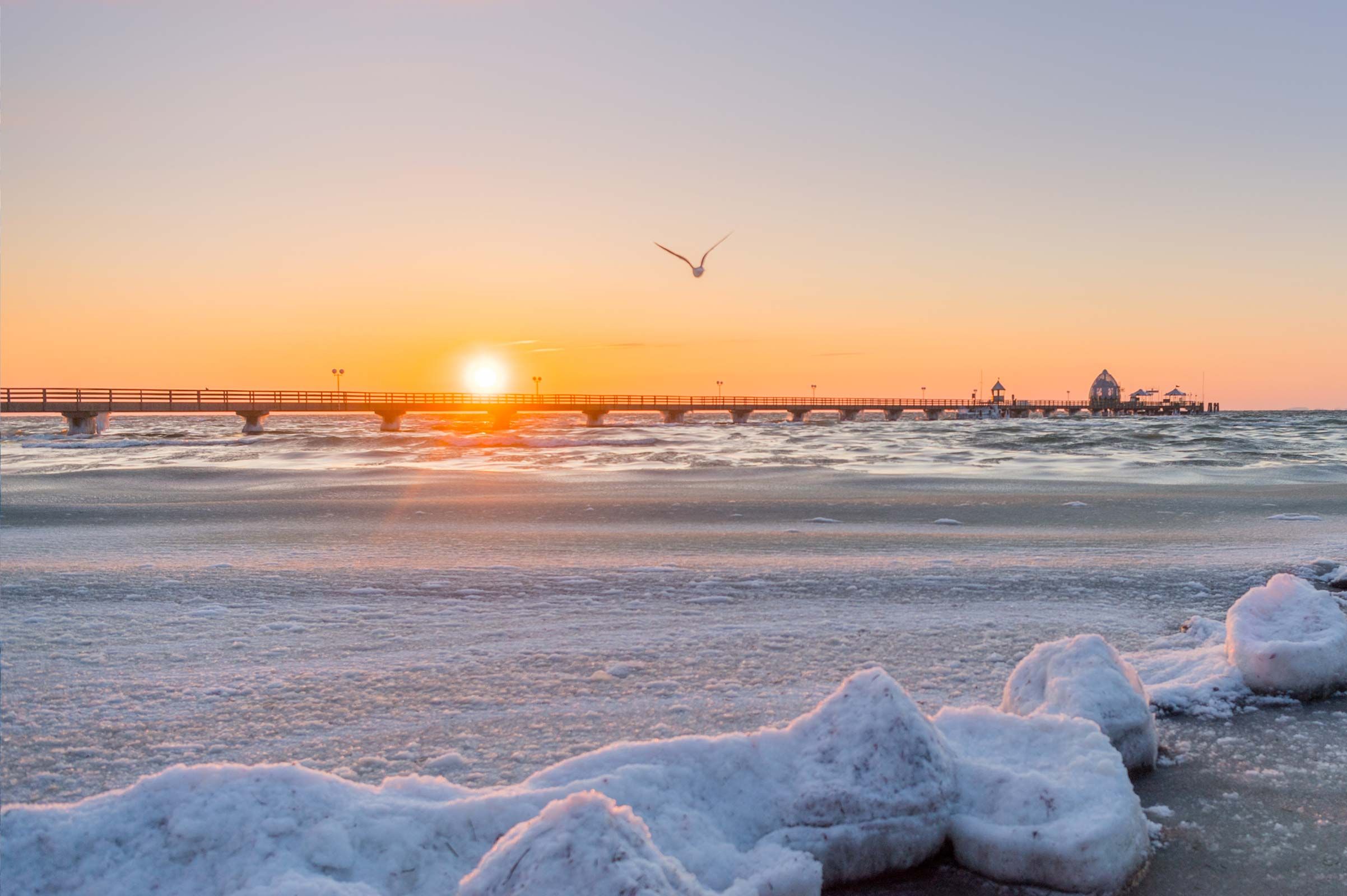 Verschneiter Strand von Grömitz mit Seebrücke im warmen Licht der tief stehenden Sonne