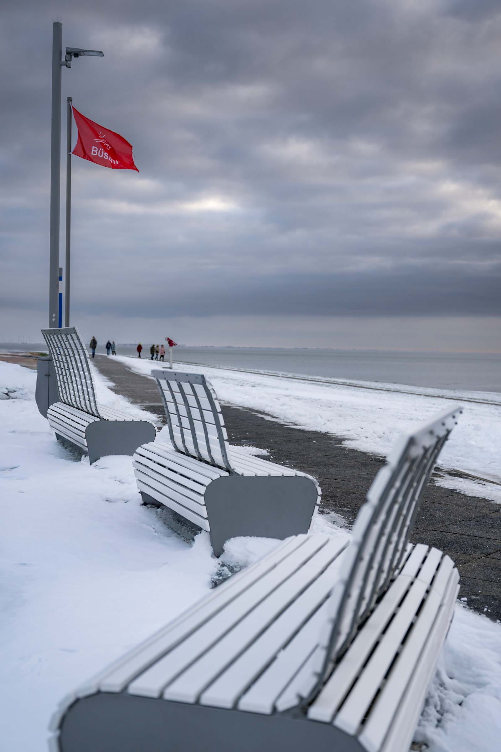 Schneebedeckte Promenade mit Bänken und Büsum-Flagge